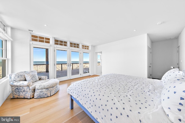 bedroom featuring visible vents, a water view, access to exterior, recessed lighting, and wood finished floors