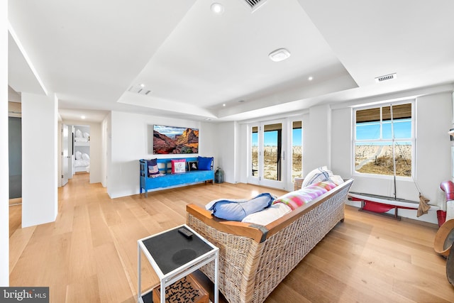 living room with light wood finished floors, recessed lighting, visible vents, and a raised ceiling