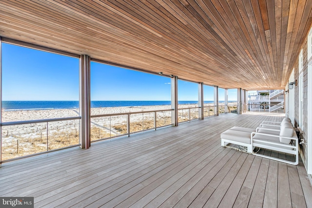 wooden deck featuring a view of the beach and a water view