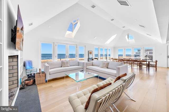 living area with visible vents, high vaulted ceiling, a skylight, and wood finished floors