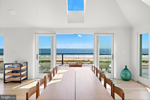 dining room featuring a beach view, light wood-type flooring, and a water view