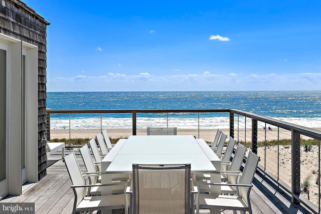 balcony featuring outdoor dining area, a view of the beach, and a water view