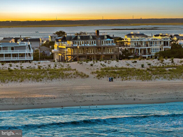 aerial view at dusk with a view of the beach and a water view