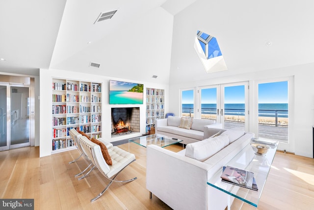 living room with visible vents, high vaulted ceiling, light wood-style flooring, and a fireplace