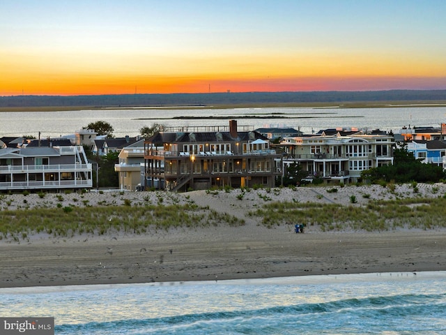 aerial view at dusk with a water view and a view of the beach