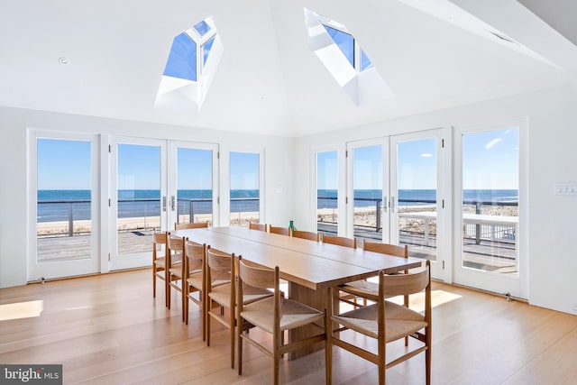 sunroom with french doors, a water view, and a skylight