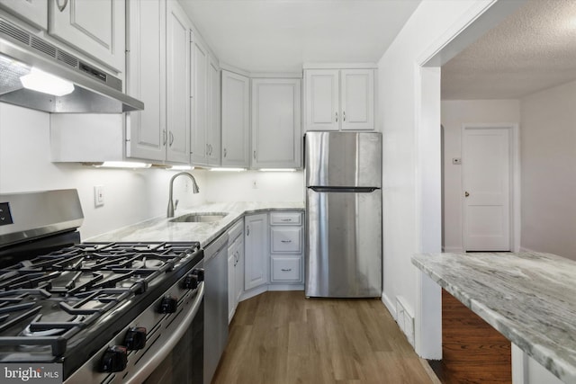 kitchen featuring light hardwood / wood-style flooring, stainless steel appliances, sink, white cabinetry, and light stone counters