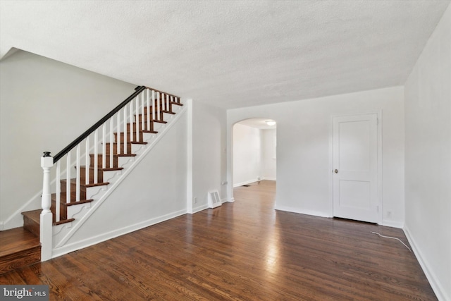 unfurnished living room featuring a textured ceiling and dark hardwood / wood-style flooring