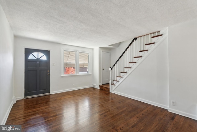 foyer entrance with a textured ceiling and dark hardwood / wood-style flooring