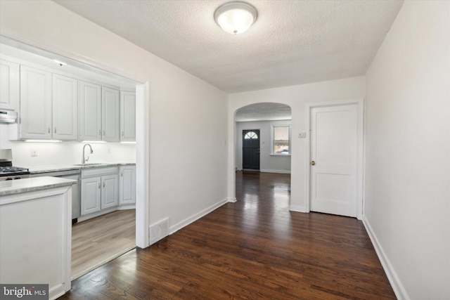 kitchen with dark hardwood / wood-style floors, sink, stove, white cabinetry, and a textured ceiling