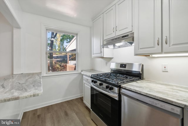 kitchen featuring white cabinetry, light stone countertops, stainless steel appliances, and light wood-type flooring