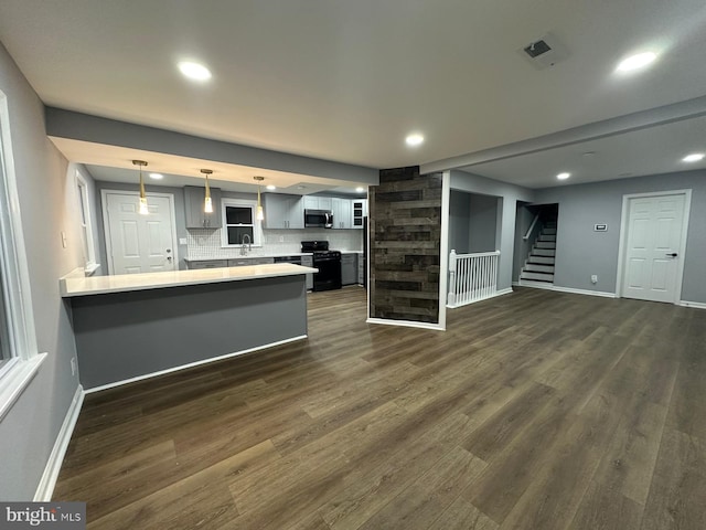 kitchen featuring black range, sink, dark hardwood / wood-style floors, tasteful backsplash, and kitchen peninsula