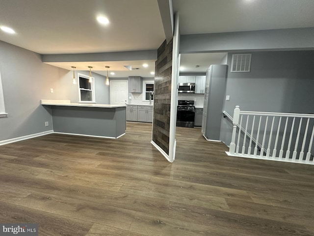 kitchen featuring kitchen peninsula, gas stove, gray cabinets, and dark hardwood / wood-style floors