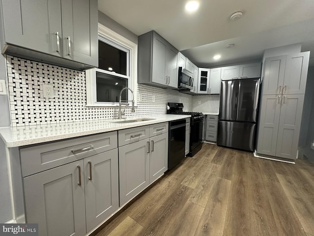 kitchen with gray cabinetry, black appliances, sink, tasteful backsplash, and dark hardwood / wood-style flooring