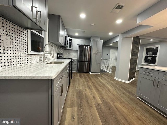 kitchen with appliances with stainless steel finishes, tasteful backsplash, gray cabinetry, dark wood-type flooring, and sink