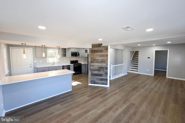 kitchen with pendant lighting, dark hardwood / wood-style flooring, backsplash, and appliances with stainless steel finishes