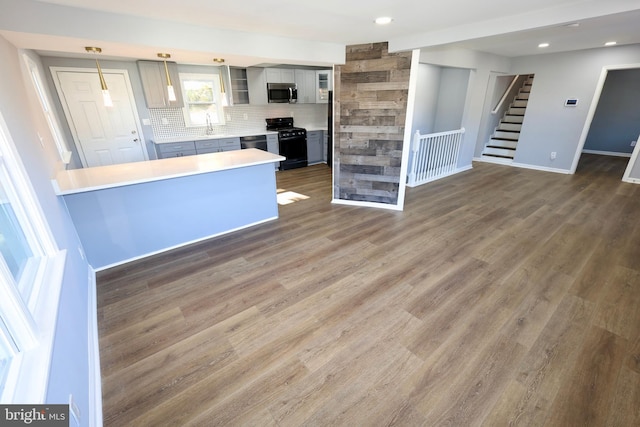 kitchen featuring tasteful backsplash, pendant lighting, black appliances, and dark hardwood / wood-style floors