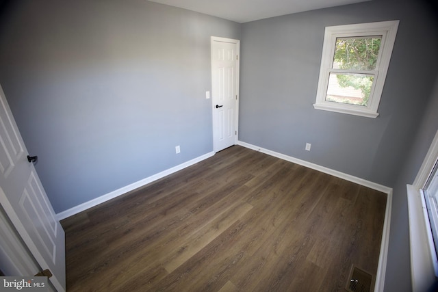 unfurnished room with dark wood-type flooring