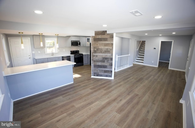 kitchen featuring gray cabinetry, dark hardwood / wood-style floors, decorative light fixtures, and appliances with stainless steel finishes