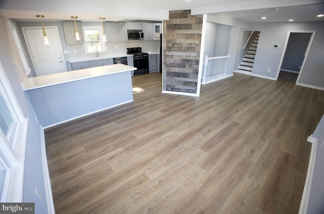 kitchen with gray cabinetry, decorative light fixtures, dark hardwood / wood-style flooring, and appliances with stainless steel finishes