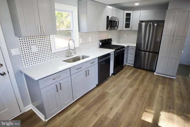 kitchen with sink, hardwood / wood-style flooring, tasteful backsplash, and black appliances