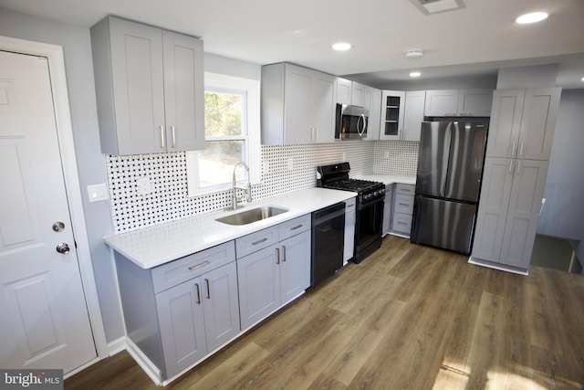 kitchen with tasteful backsplash, sink, black appliances, and wood-type flooring