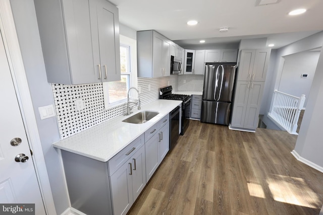 kitchen featuring sink, tasteful backsplash, dark hardwood / wood-style flooring, gray cabinets, and black appliances