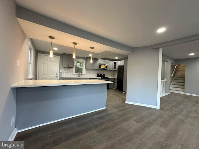 kitchen with dark wood-type flooring, gray cabinets, tasteful backsplash, kitchen peninsula, and stainless steel appliances