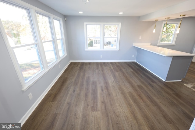 kitchen featuring kitchen peninsula, hanging light fixtures, and dark wood-type flooring