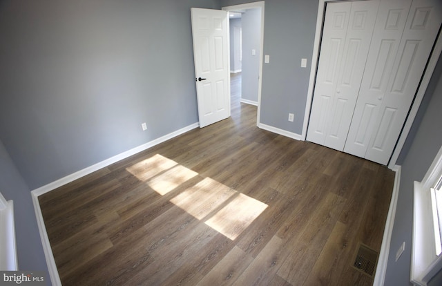 unfurnished bedroom with a closet and dark hardwood / wood-style floors