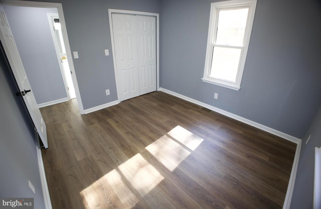 unfurnished bedroom featuring dark hardwood / wood-style floors and a closet