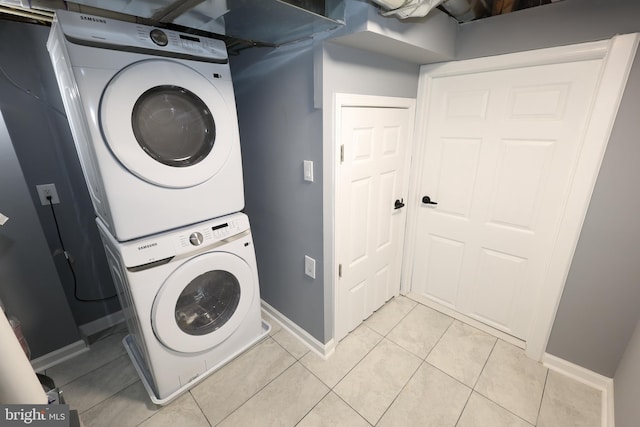 laundry area with stacked washer and dryer and light tile patterned floors