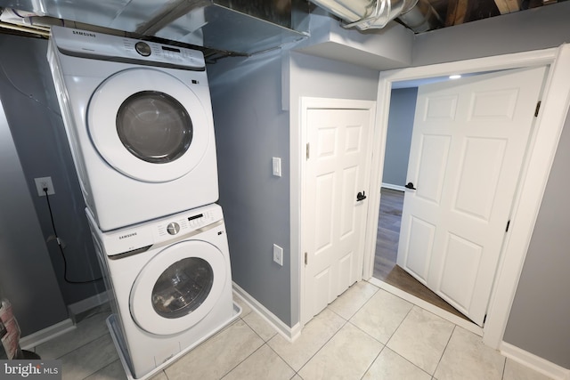 clothes washing area featuring light tile patterned floors and stacked washer and clothes dryer