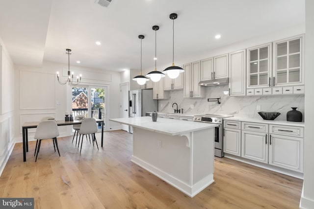 kitchen with white cabinetry, stainless steel appliances, light wood-type flooring, and a kitchen island