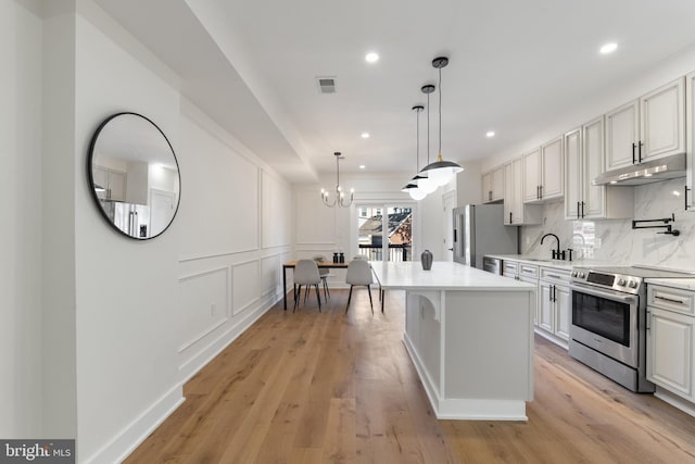 kitchen with a center island, white cabinetry, light hardwood / wood-style floors, stainless steel appliances, and decorative light fixtures