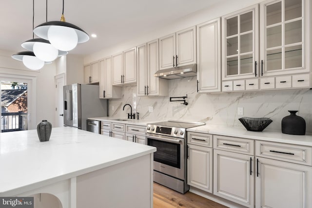 kitchen with decorative light fixtures, stainless steel appliances, sink, and backsplash