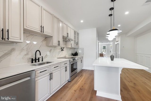 kitchen with appliances with stainless steel finishes, light hardwood / wood-style flooring, white cabinetry, and sink