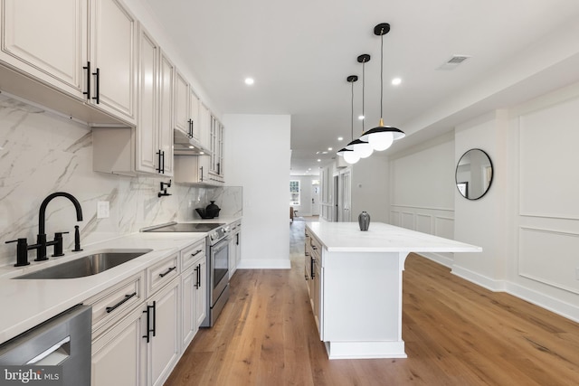 kitchen with a kitchen island, stainless steel appliances, sink, light wood-type flooring, and white cabinetry