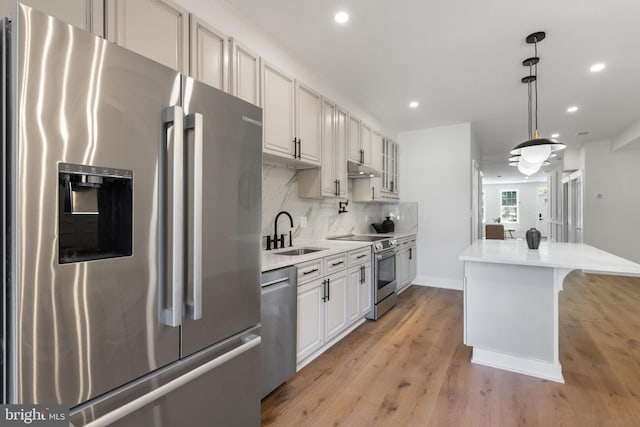 kitchen featuring appliances with stainless steel finishes, sink, a center island, white cabinetry, and light hardwood / wood-style floors