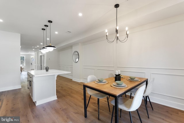 dining space with wood-type flooring and an inviting chandelier