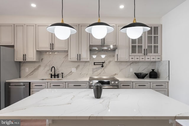 kitchen with appliances with stainless steel finishes, tasteful backsplash, sink, and light stone countertops