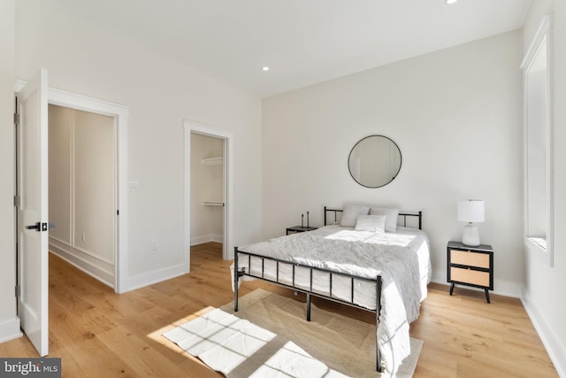 bedroom featuring light hardwood / wood-style flooring and a walk in closet