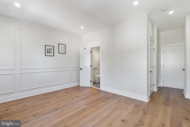 unfurnished bedroom featuring ensuite bathroom and light hardwood / wood-style flooring