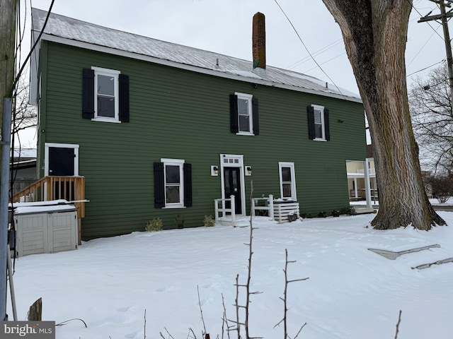 snow covered property featuring metal roof and a chimney