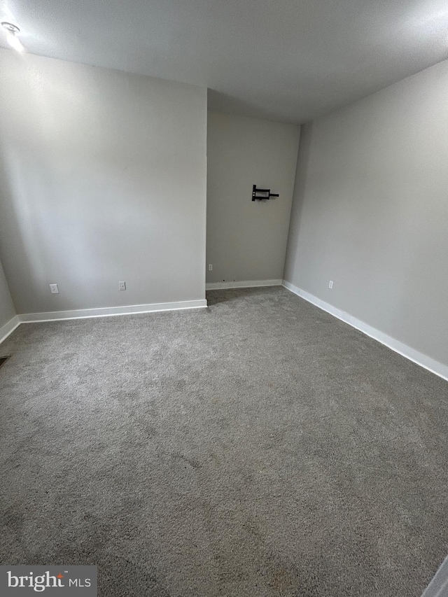 carpeted spare room featuring baseboards