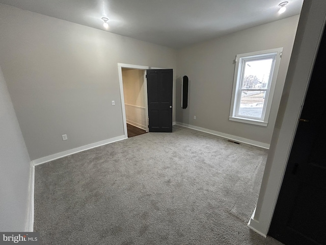 empty room featuring carpet flooring, visible vents, and baseboards