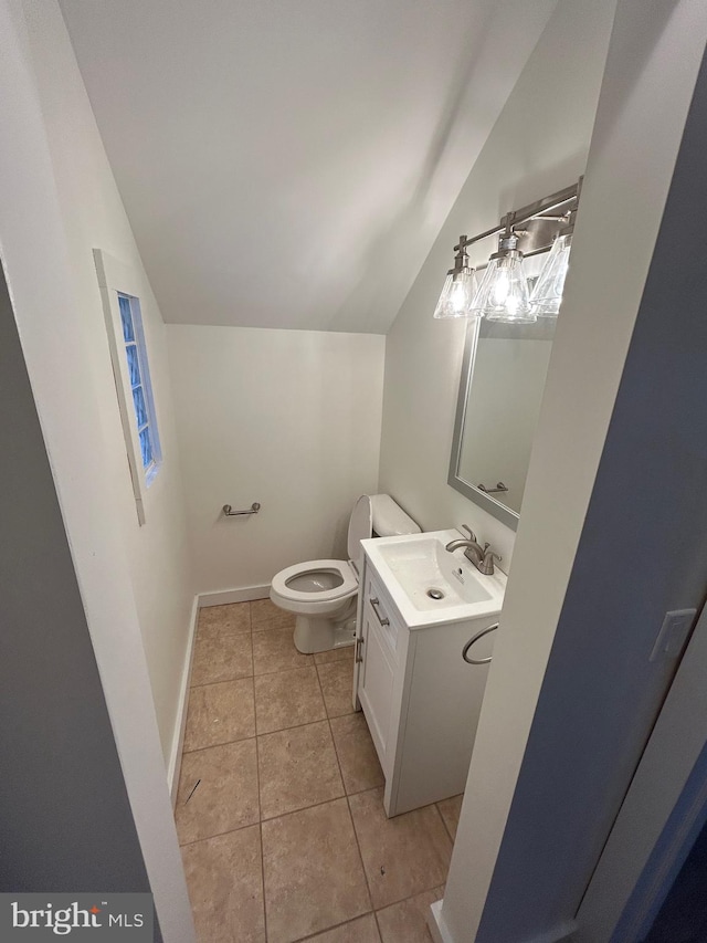 bathroom with toilet, vaulted ceiling, vanity, tile patterned flooring, and baseboards