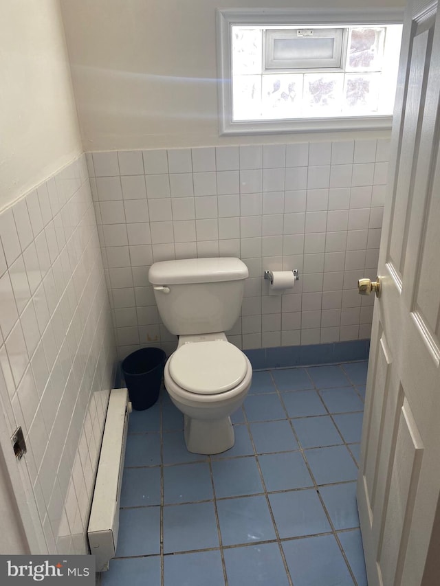 bathroom featuring tile walls, a baseboard radiator, toilet, and tile patterned flooring