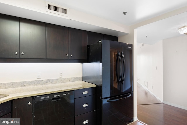 kitchen featuring hardwood / wood-style floors, black appliances, and light stone counters