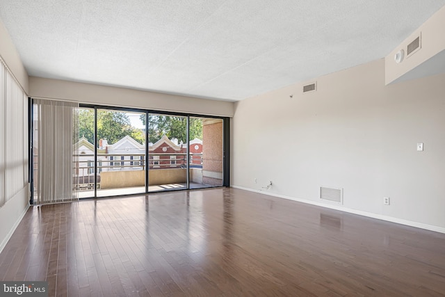 unfurnished room with a textured ceiling and dark hardwood / wood-style floors